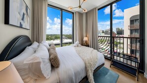 A modern hotel room with a large bed, a view of the city, and a balcony with a railing. - Nomad Stlysh (Miami)