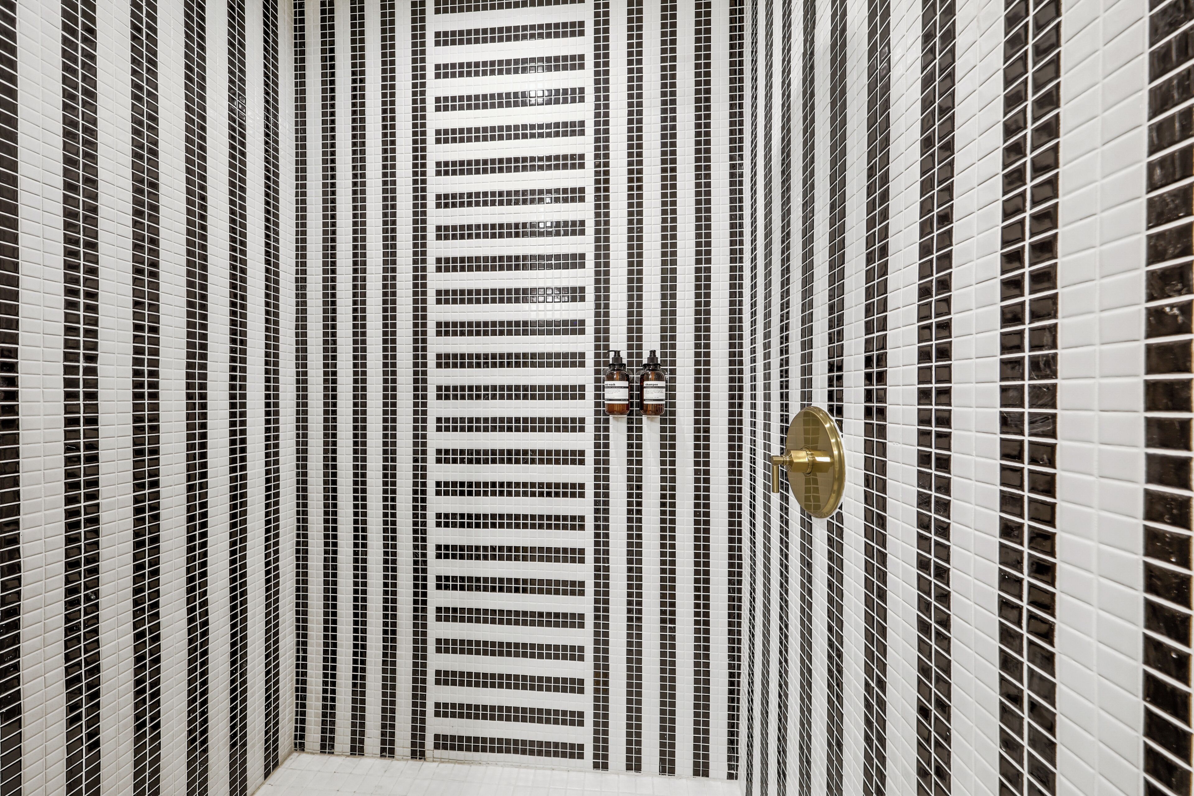 Un pasillo con una pared de baldosas estampadas y una puerta con pomo de latón.