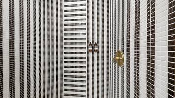 Un pasillo con una pared de baldosas estampadas y una puerta con pomo de latón.