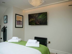 Habitación de hotel con cama, dos toallas, un radiador y una obra de arte en la pared.