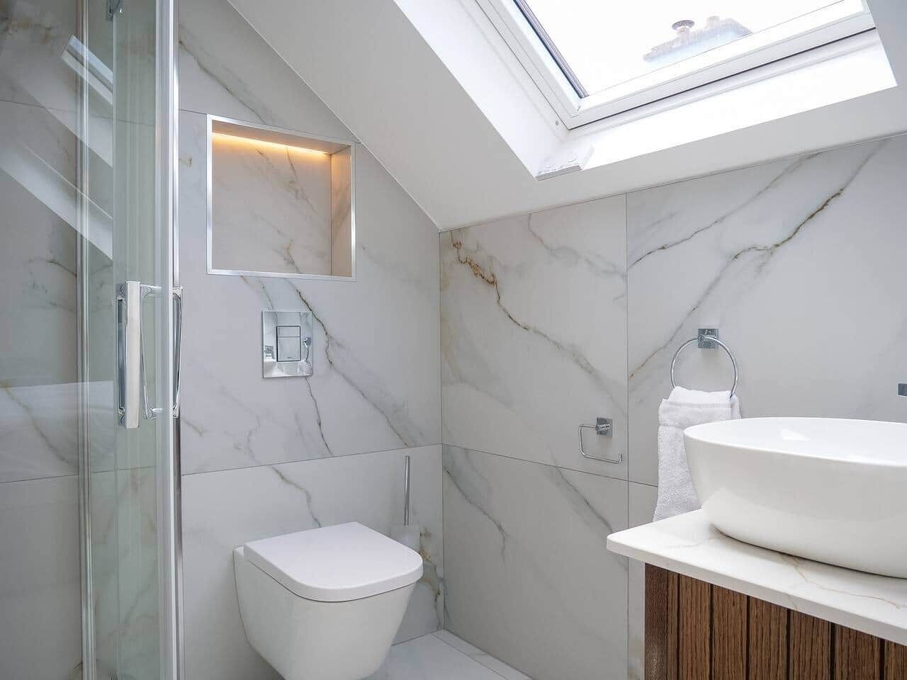 A modern bathroom with a skylight, a glass shower enclosure, a toilet, and a sink with a wooden vanity.