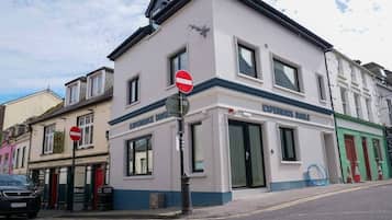 A building with a 'No Entry' sign, a shop named 'Experience Dinges,' and a car parked on the street.