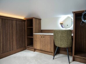 Una habitación con un armario de madera, un escritorio con espejo y una silla.