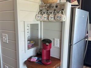 A kitchen with a coffee station, a red coffee maker, and a shelf with a coffee mug.