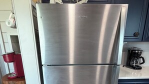 A stainless steel refrigerator in a kitchen with a coffee maker and a kettle on the counter.
