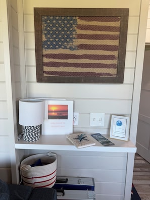 A wall-mounted American flag, a welcome sign, a lamp, a framed picture, a globe with internet details, and a striped bag.