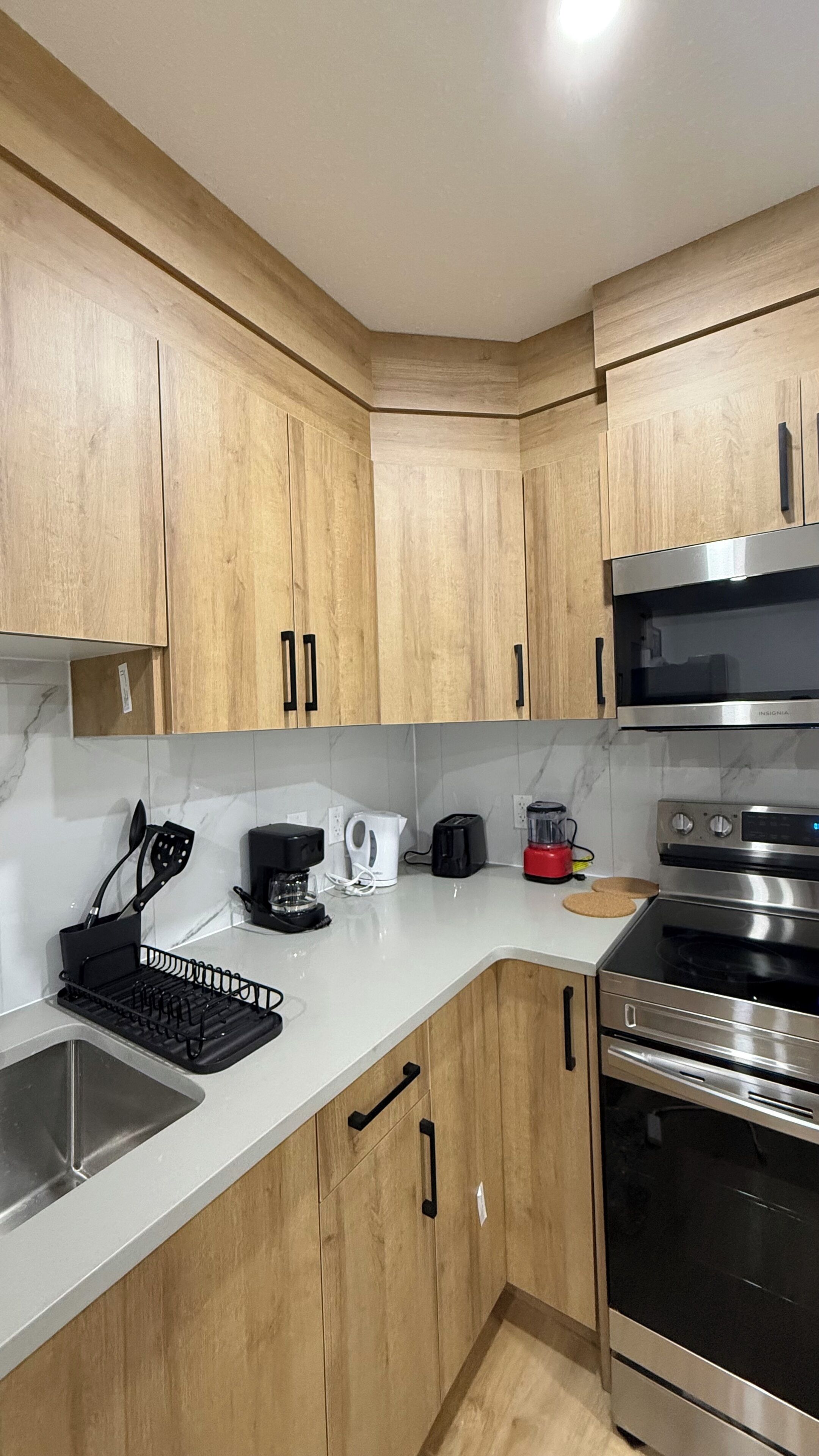 Een moderne keuken met houten kastjes, roestvrijstalen apparatuur, een spoelbak en een koffiezetapparaat.