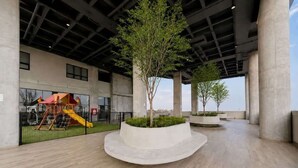 Un atrium intérieur doté d’une aire de jeux, d’un arbre central et offrant une vue sur le ciel.