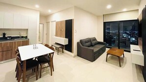 Un appartement moderne comprenant un coin repas, un canapé, une télévision et une vue sur la ville.