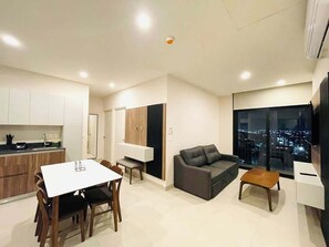 Eine moderne Wohnung mit Essbereich, einer Couch, einem Fernseher und Blick auf die Stadt.