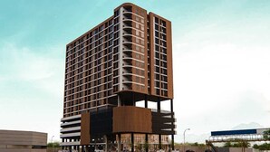 Un immeuble moderne de grande hauteur, doté de nombreux balcons, d’un toit plat et d’un atrium central.
