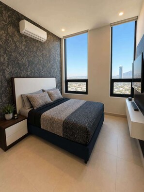 Ein Schlafzimmer mit Bett, Nachttisch, Blumentopf und einem großen Fenster mit Blick auf die Stadt.