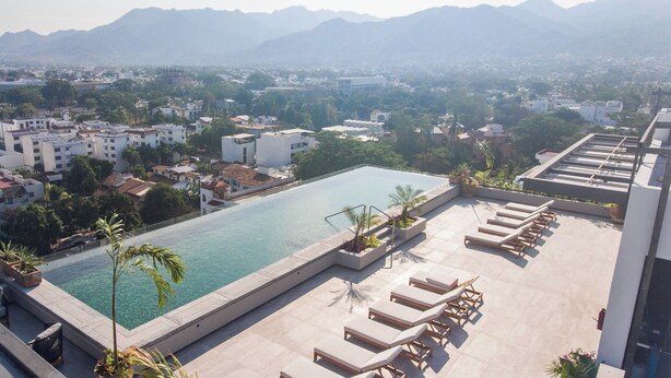 A rooftop pool with lounge chairs and a view of a cityscape and mountains. - Modern Versalles 2BR w/ Rooftop Pool & Views in Puerto Vallarta (Puerto Vallarta)