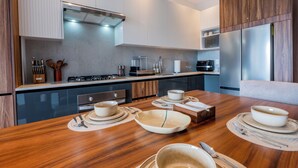 A modern kitchen with a dining area, featuring a wooden table, stainless steel appliances, and a built-in oven. - Modern Versalles 2BR w/ Rooftop Pool & Views in Puerto Vallarta (Puerto Vallarta)