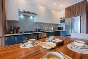 A modern kitchen with a dining area, featuring a wooden table, stainless steel appliances, and a built-in oven. - Modern Versalles 2BR w/ Rooftop Pool & Views in Puerto Vallarta (Puerto Vallarta)