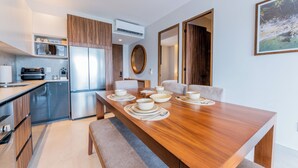 A modern kitchen with built-in appliances, a dining area with a wooden table set for four, and a view of a tropical landscape through an open door. - Modern Versalles 2BR w/ Rooftop Pool & Views in Puerto Vallarta (Puerto Vallarta)