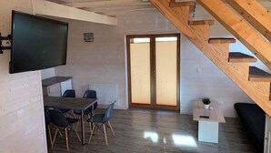 A modern interior with a dining area, a TV mounted on the wall, a staircase, and a sliding glass door.