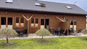 A wooden building with a tiled roof, large windows, and outdoor seating.