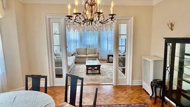 A spacious living room with a chandelier, a sofa set, a coffee table, and a fireplace. - Spacious 3BR /7 Guests/ Parking/Near NYC & Stadium (Bayonne)