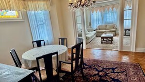 A dining area with a round table, chairs, a chandelier, and a patterned rug. - Spacious 3BR /7 Guests/ Parking/Near NYC & Stadium (Bayonne)