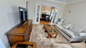 A living room with a sofa, coffee table, TV, and a patterned rug. - Spacious 3BR /7 Guests/ Parking/Near NYC & Stadium (Bayonne)