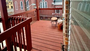 A wooden deck with a railing, a chair, and a potted plant. - Spacious 3BR /7 Guests/ Parking/Near NYC & Stadium (Bayonne)