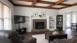 A living room with a fireplace, leather sofas, a TV, and wooden beams on the ceiling. - 3 Bedroom Backyard Oasis Near FIFA World Cup Events (Blue Springs)