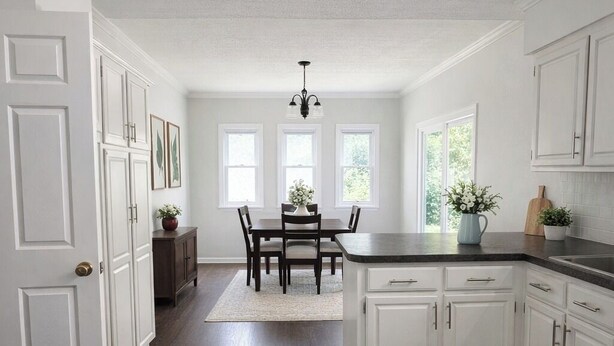 A kitchen with white cabinetry, a dining table with chairs, a chandelier, and a view through the windows. - 3 Bedroom Backyard Oasis Near FIFA World Cup Events (Blue Springs)