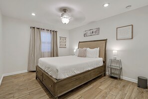 Ein Schlafzimmer mit einem hölzernen Bett, einem Nachttisch, einer Wandlampe und einem Deckenventilator.