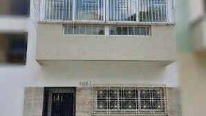 Um edifício de vários andares com janelas protegidas por grades e um portão preto.