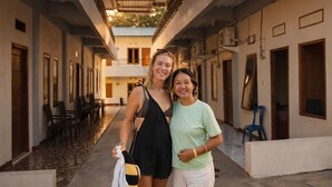 A corridor with a high ceiling, chairs, and tables, suggesting a dining or lounge area. - Ocha Bajo Homestay (Labuan Bajo)