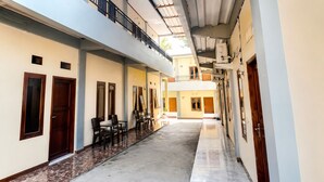 A corridor with doors, windows, and chairs. - Ocha Bajo Homestay (Labuan Bajo)