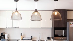 Et moderne køkken med hængende lamper, indbygget mikrobølgeovn og kaffemaskine.