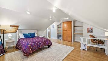 A bedroom with a bed, a desk, a chair, a lamp, a wardrobe, and a shelf.