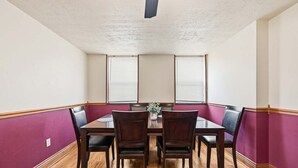 Ein Esszimmer mit Holztisch, sechs Stühlen und einem Blumenarrangement.