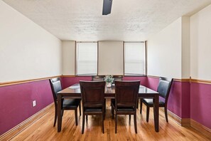 Ein Esszimmer mit Holztisch, sechs Stühlen und einem Blumenarrangement.