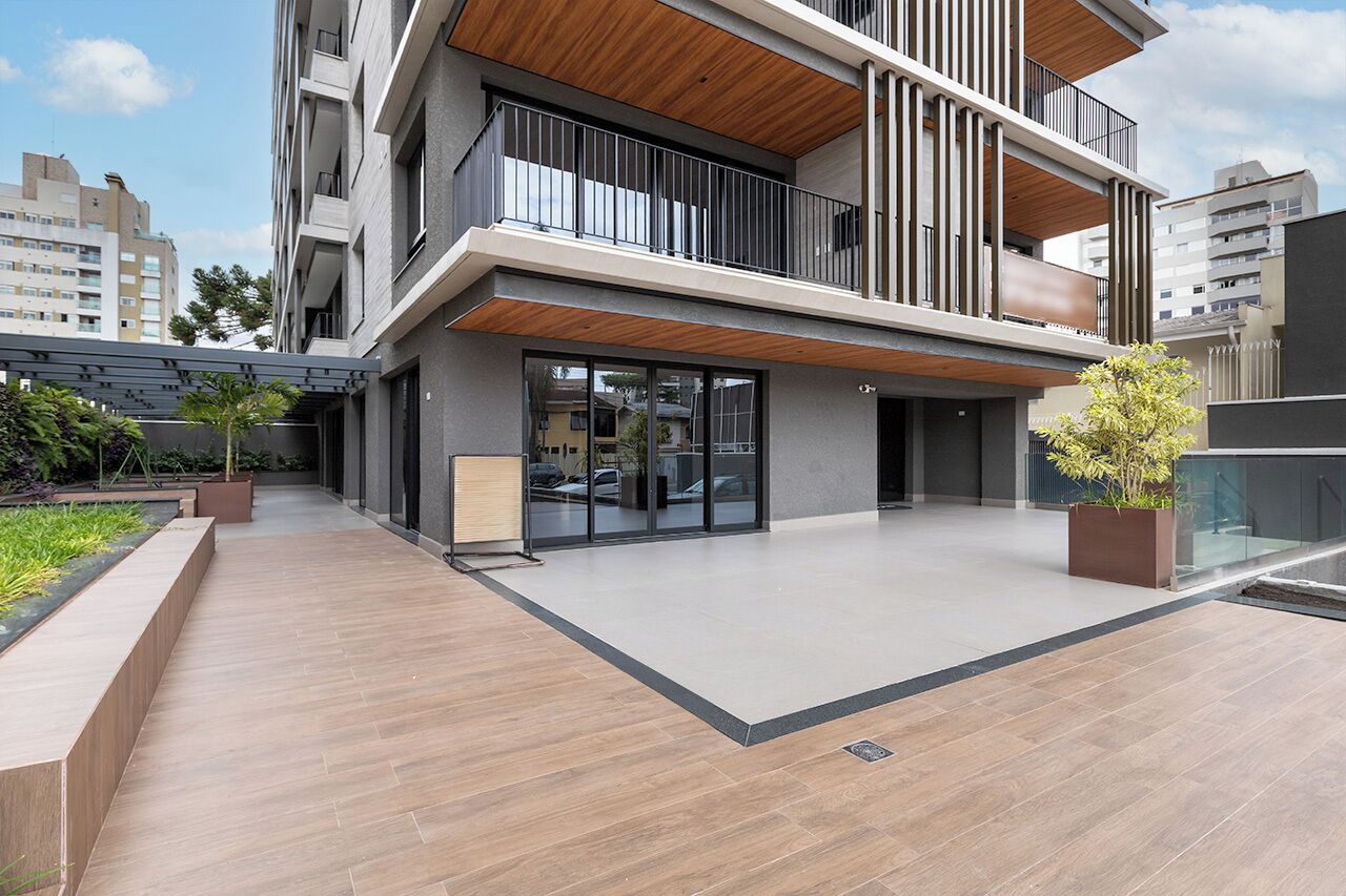 A modern building with a flat roof, large windows, and a covered outdoor area with a wooden deck.