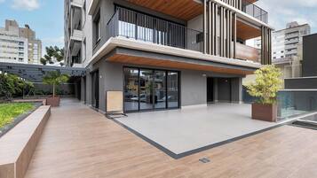 A modern building with a flat roof, large windows, and a covered outdoor area with a wooden deck.