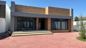 A modern two-story building with large glass windows, a flat roof, and a brick-paved entrance area. - Villa warm pool (Баку)