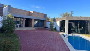 A modern house with a swimming pool, a patio, and a small garden. - Villa warm pool (Баку)
