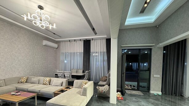 A modern living room with a sectional sofa, a coffee table, and a glass door leading to a balcony. - Villa warm pool (Баку)