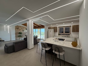 A modern kitchen with a central island, bar stools, and a stone accent wall. - Villa Heaven Nature (Lazio)