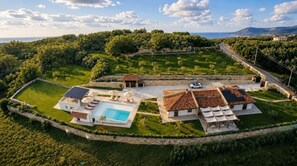 Eine Villa mit Schwimmbad, Sitzgelegenheiten im Freien und Meerblick.