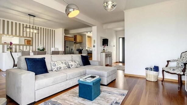 A modern living room with a sectional sofa, a coffee table, and a dining area in the background. - Zen House By The Madeira Luxury Collection (Arco da Calheta)