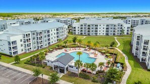 A modern apartment complex with a central swimming pool, outdoor seating, and a well-maintained lawn. - Storey Lake Cozy 3BR Condo, Lake View, By Disney (Kissimmee)