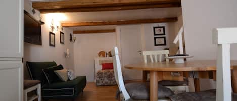 A cozy room with a wooden dining table, a green sofa, and a staircase leading to an upper level.