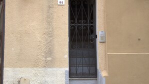 Eine Gebäudefassade mit einem Metallgitter, einer Tür und einem kleinen Schild mit der Nummer 64.