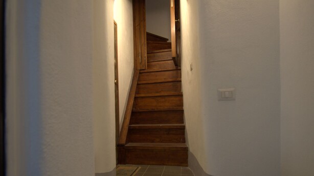 Ein schmaler Flur mit einer Holztreppe, die zu einer Empore führt.