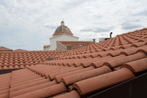 Tejas de terracota, un edificio blanco con una cúpula y un cielo nublado.