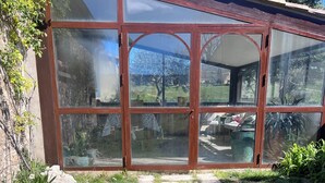 Une véranda avec une porte vitrée, un jardin agrémenté de pas japonais et une vue sur l’extérieur.